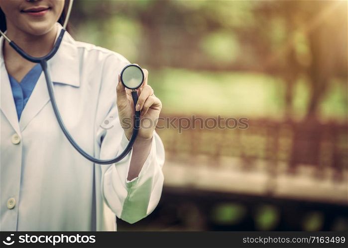 Young female doctor pointing stethoscope at blank space. Medical healthcare concept.