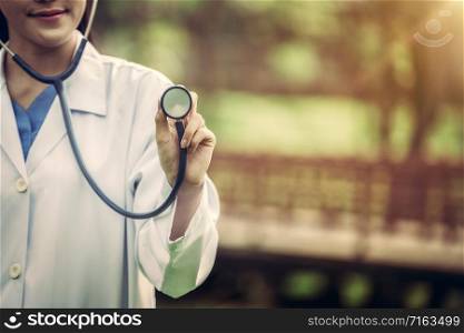 Young female doctor pointing stethoscope at blank space. Medical healthcare concept.