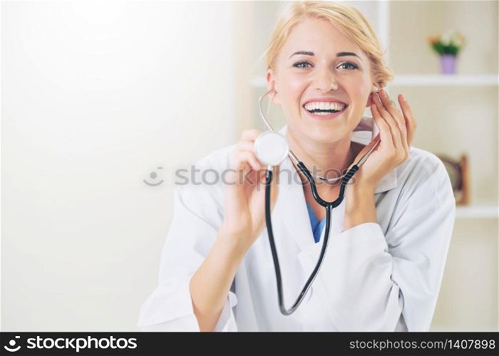 Young female doctor pointing stethoscope at blank space. Selective focus at doctors face. Medical healthcare concept.. Female doctor pointing stethoscope at blank space.