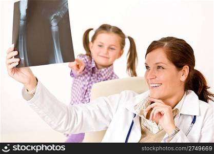 Young female doctor show x-ray to child at medical office