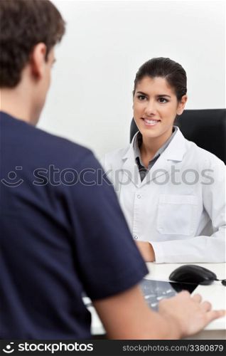 Young female doctor talking to the patient in her office