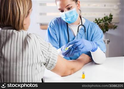 Young female doctor vaccinating elderly patient in UK GP&rsquo;s office,virus disease therapy and treatment,remedy and cure for infections or seasonal flu,Coronavirus COVID-19 potential vaccine development