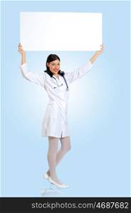 Young female doctor with a banner. Portrait of happy successful young female doctor holding blank banner
