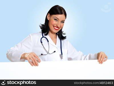 Young female doctor with a banner. Portrait of happy successful young female doctor holding blank banner