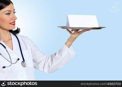 Young female doctor with a banner. Portrait of happy successful young female doctor holding blank banner