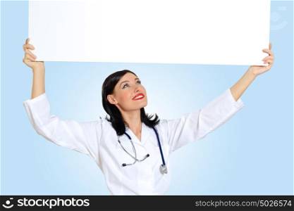 Young female doctor with a banner. Portrait of happy successful young female doctor holding blank banner