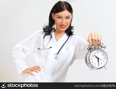 Young female doctor with clocks. Portrait of happy successful young female doctor holding clocks