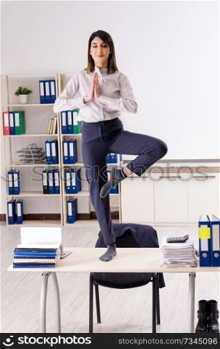 Young female employee doing exercises at workplace 