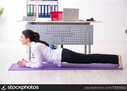 Young female employee doing exercises in the office 