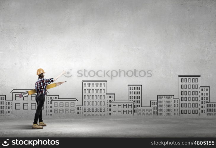 Young female engineer in hard hat with big pencil. Woman architect