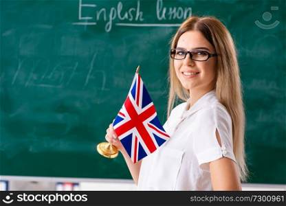 Young female english language teacher standing in front of the blackboard   . Young female english language teacher standing in front of the b