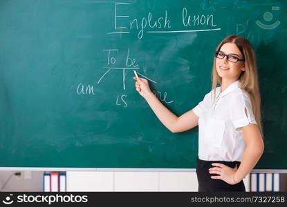 Young female english language teacher standing in front of the blackboard . Young female english language teacher standing in front of the b