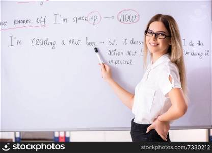 Young female english language teacher standing in front of the blackboard . Young female english language teacher standing in front of the b