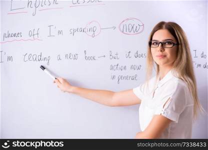 Young female english language teacher standing in front of the blackboard   . Young female english language teacher standing in front of the b