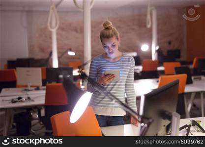 young female entrepreneur working on digital tablet in night office