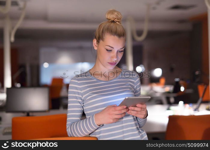 young female entrepreneur working on digital tablet in night office