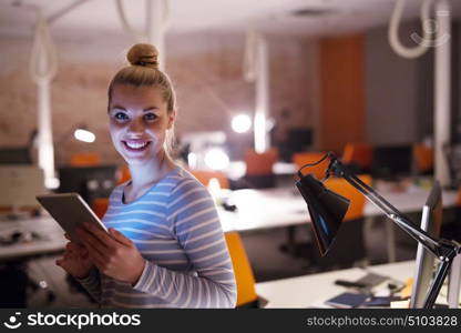 young female entrepreneur working on digital tablet in night office