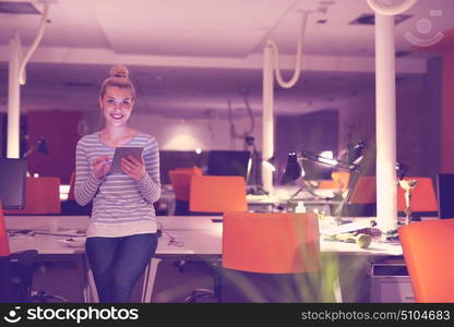 young female entrepreneur working on digital tablet in night office