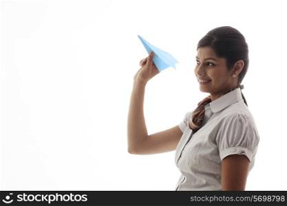 Young female executive about to throw paper airplane on white background