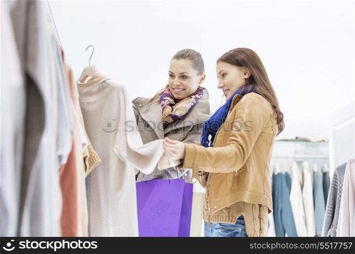 Young female friends choosing sweater in store
