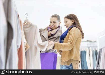 Young female friends choosing sweater in store