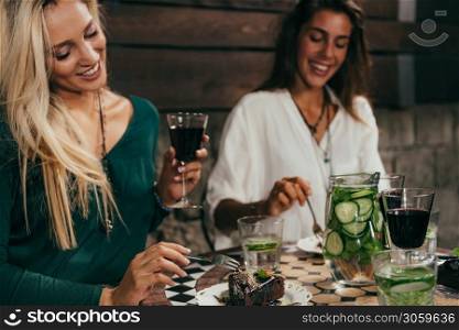 Young Female Friends Eating Cakes and Drinking Wine