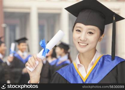 Young Female Graduate Holding Diploma, Portrait
