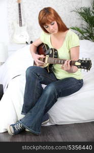 Young female guitarist at home