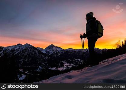 Young female hiker looking out from mountainside at dusk, Reutte, Tyrol, Austria