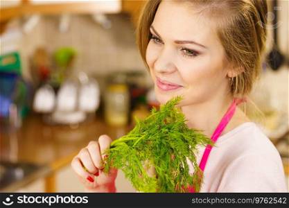 Young female holding herbs. Pretty woman having dill herb about to cook something.. Young woman holding dill herb
