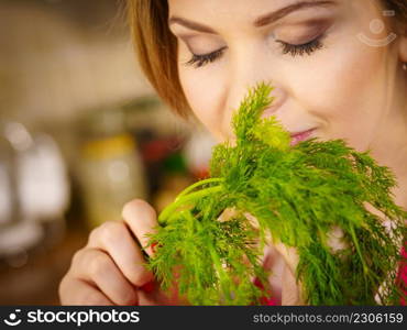 Young female holding herbs. Pretty woman having dill herb smelling it scent.. Young woman holding dill herb