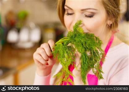 Young female holding herbs. Pretty woman having dill herb smelling it scent.. Young woman holding dill herb