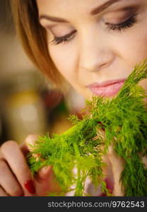 Young female holding herbs. Pretty woman having dill herb smelling it scent.. Young woman holding dill herb