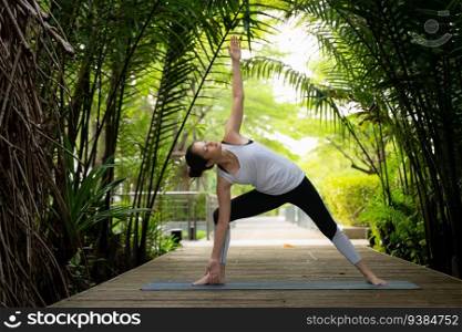 Young female in the garden there are wooden walkways and a tunnel of fresh green trees, with yoga activities for health
