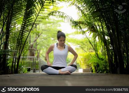 Young female in the garden there are wooden walkways and a tunnel of fresh green trees, with yoga activities for health