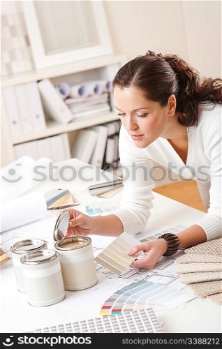 Young female interior designer at office with paint and color swatch