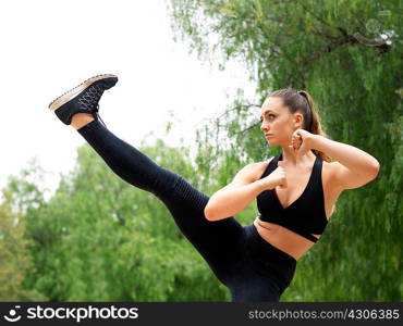 Young female kickboxer practicing kickboxing in park