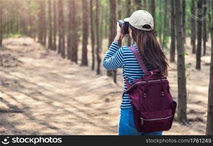 Young female lifestyle photographer travel in forest nature with backpack abd copy space.