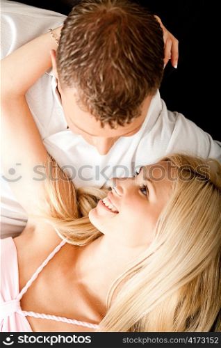 Young female lying on man&rsquo;s lap and pulling him towards herself