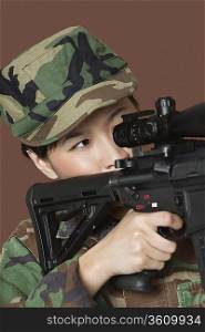Young female Marine Corps soldier aiming M4 assault rifle over brown background