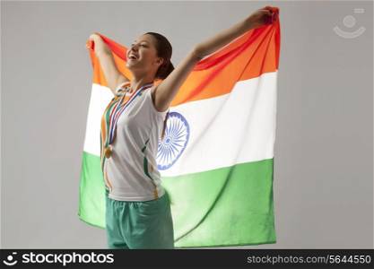 Young female medalist celebrating victory with Indian flag isolated over gray background