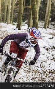 Young female mountain biker riding downhill through forest