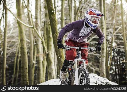 Young female mountain biker riding through forest