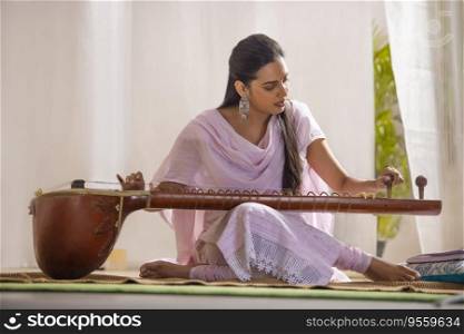 Young female musician tuning her sitar while sitting in living room