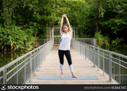 Young female on a wooden bridge in the park with healthy yoga activities