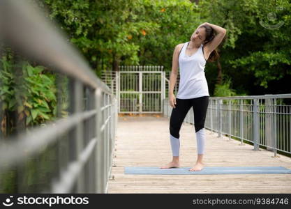 Young female on a wooden bridge in the park with healthy yoga activities