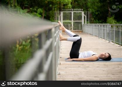 Young female on a wooden bridge in the park with healthy yoga activities
