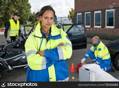 Young female paramedic posing confidently in front of a car accident site