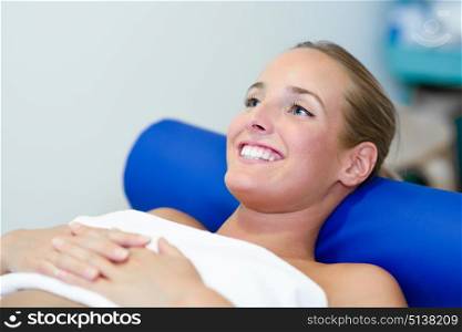 Young female patient on bed in a physiotherapy center. Blonde woman with blue eyes.