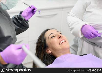 Young female patient visiting dentist office.Beautiful woman sitting at dental chair with open mouth during oral checkup while doctor working at teeth. High quality photo. Young female patient visiting dentist office. Beautiful woman sitting at dental chair with open mouth during oral checkup while doctor working at teeth